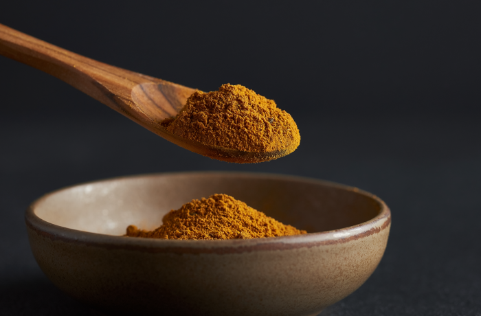 Firefly_A -spoon shot-—a wooden spoon lifting from a bowl of bright Cumin Powder, showing the 480298