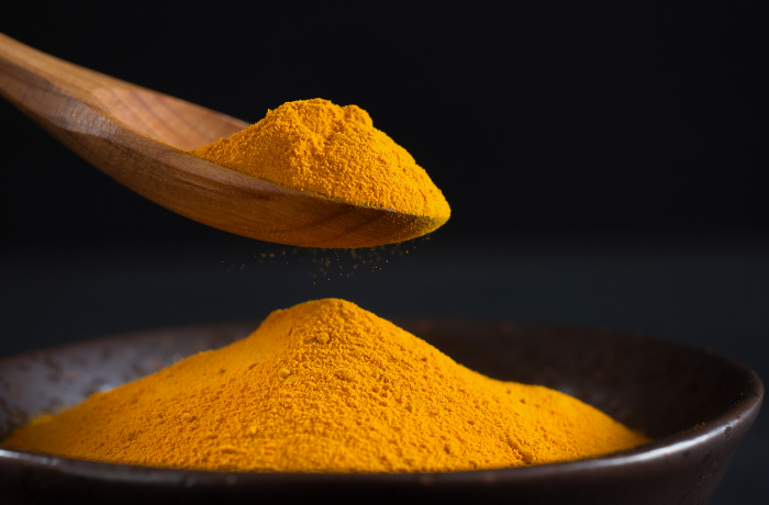 Firefly_A -spoon shot-—a wooden spoon lifting from a bowl of bright yellow turmeric Powder, s 480298